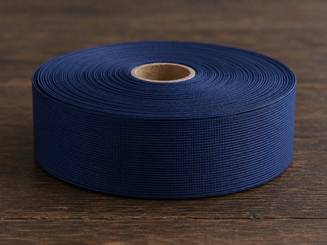 A roll of navy grosgrain ribbon on a dark wooden table